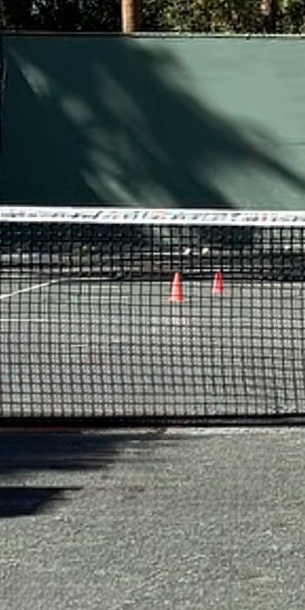 Training cones scattered on a court behind the net